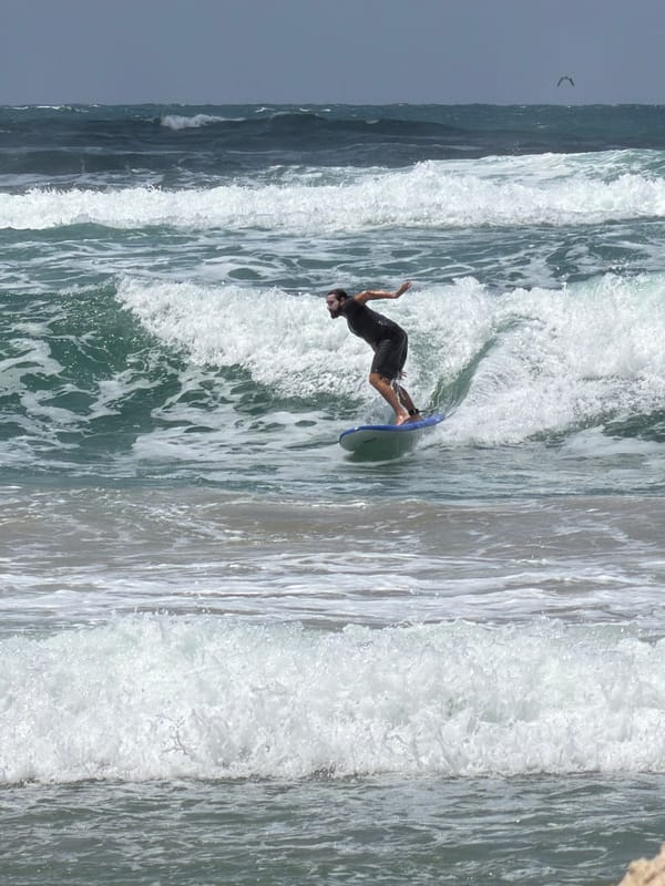 Man skimboards in choppy waters off Tel Aviv beach