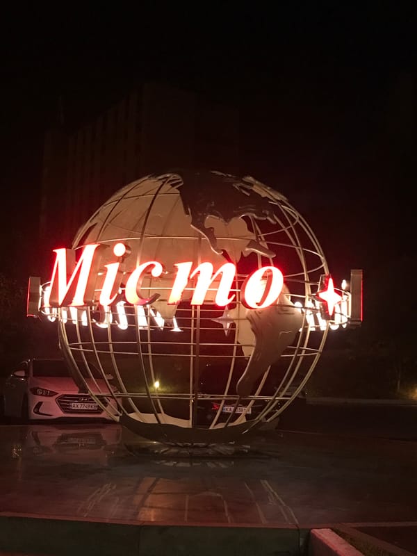 Illuminated wireframe globe sculpture with red neon signage at night