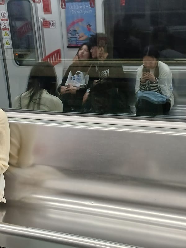 Train passengers reflected in windows during Chongqing metro ride