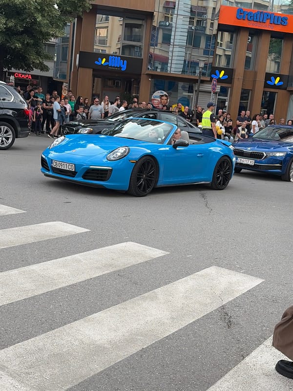 Luxury car parade with balloon-decorated motorcycles draws street crowds