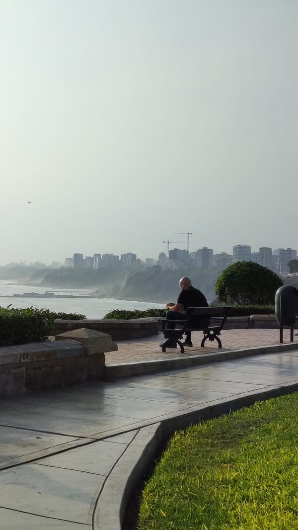 Man sits on bench overlooking ocean in Barranco
