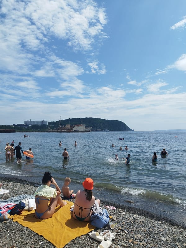 Summer day at a Vladivostok pebble beach, Golden Horn Bay backdrop.