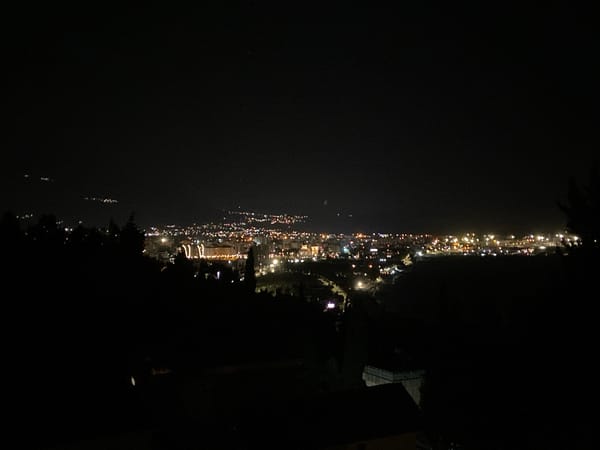 Nighttime aerial view captures illuminated Šušanj, Montenegro cityscape