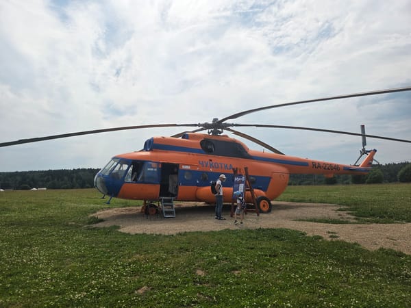 Chukotka-registered helicopter parked on gravel pad in Russian field