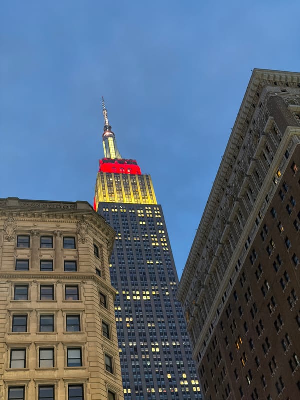 Empire State Building glowing red and yellow on a Midtown night