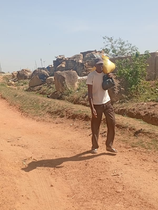Man carries large sack while walking dirt road in Nigeria