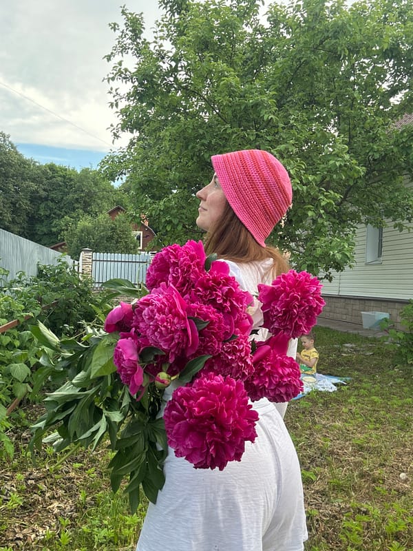 Woman poses with pink peonies in Nizhny Novgorod backyard photoshoot