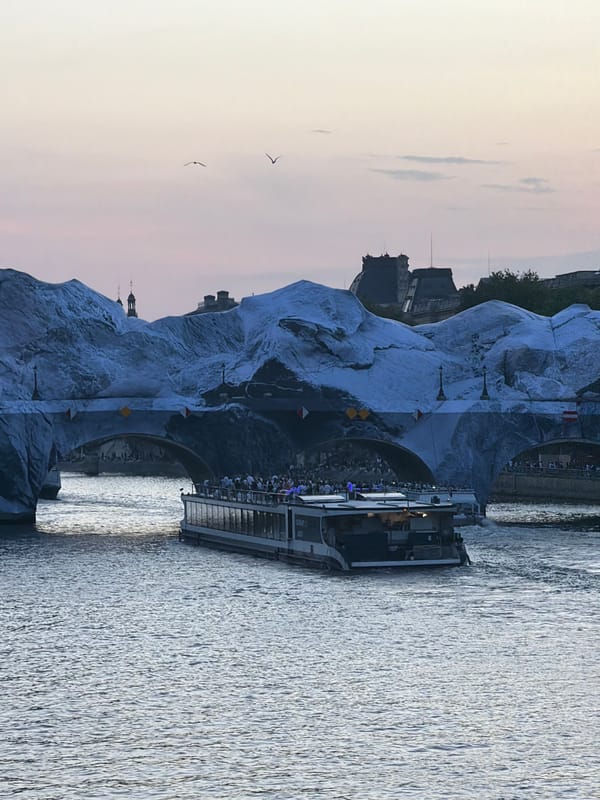 Tour boat passes under covered bridge in Paris evening