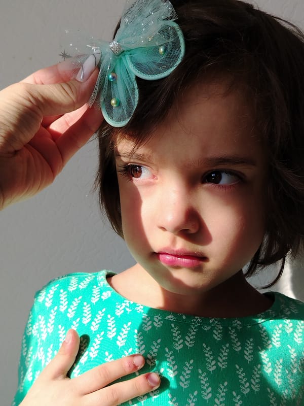 Young girl in green leaf-pattern shirt observed indoors