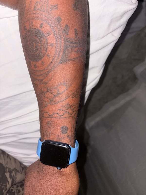 Tattooed person resting on bed photographed in Nigeria