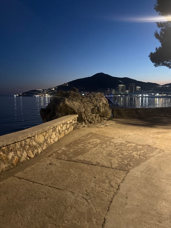 Budva Riviera at dusk — promenade, beach, and lit waterfront