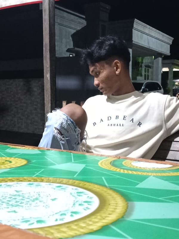 Man sits outdoors at night table in Lhokseumawe