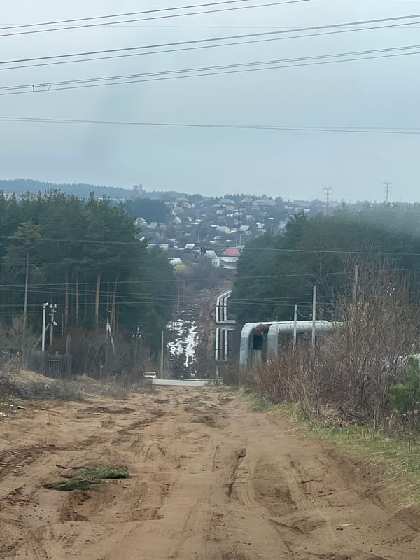 Tractor operation observed in rural Chaikovsky amid industrial landscape