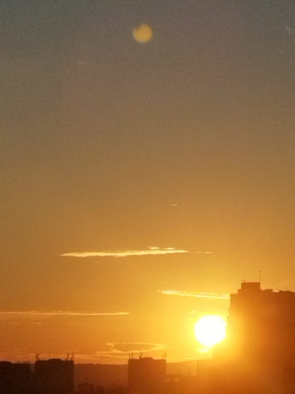 Urban sunset observed with orange-blue sky gradient over cityscape