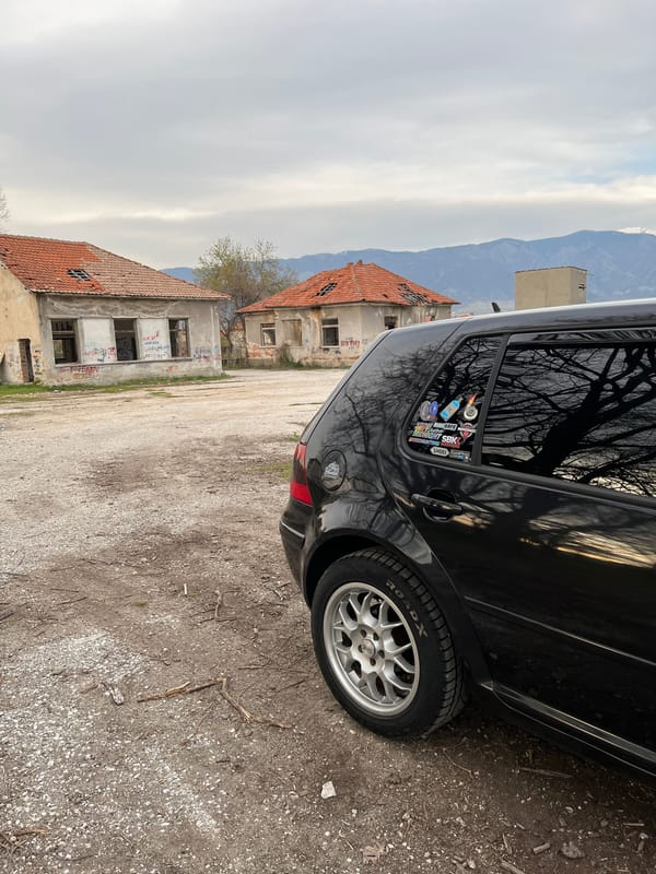 Black car parked near dilapidated buildings in Karavelovo, Bulgaria