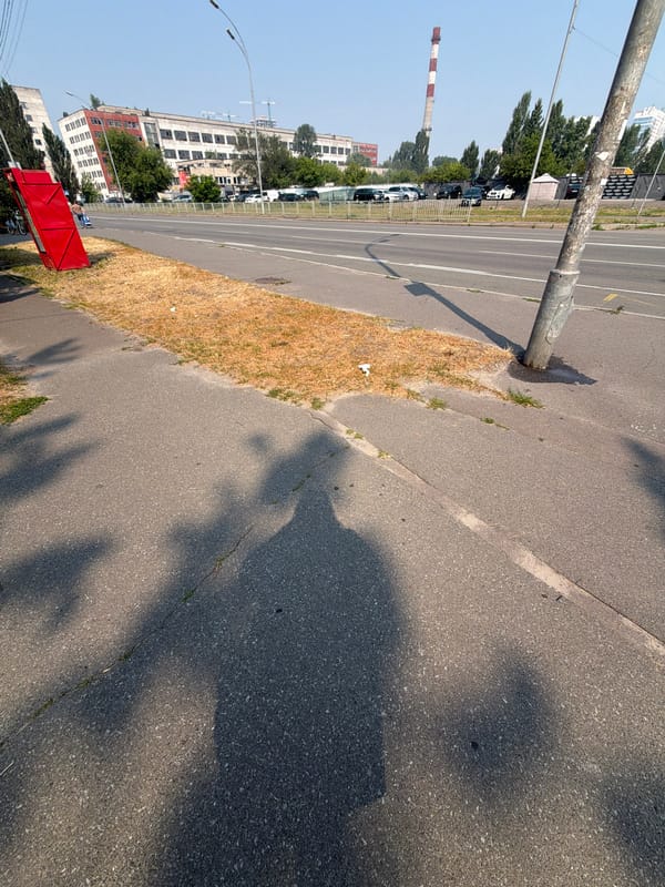 Summer morning on a Kyiv sidewalk near a red kiosk