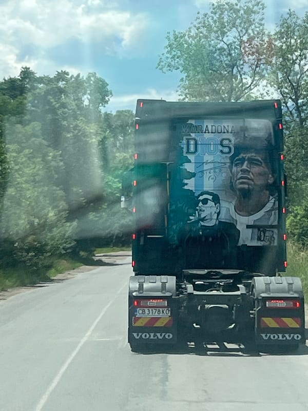 Truck displays Diego Maradona mural while driving on road