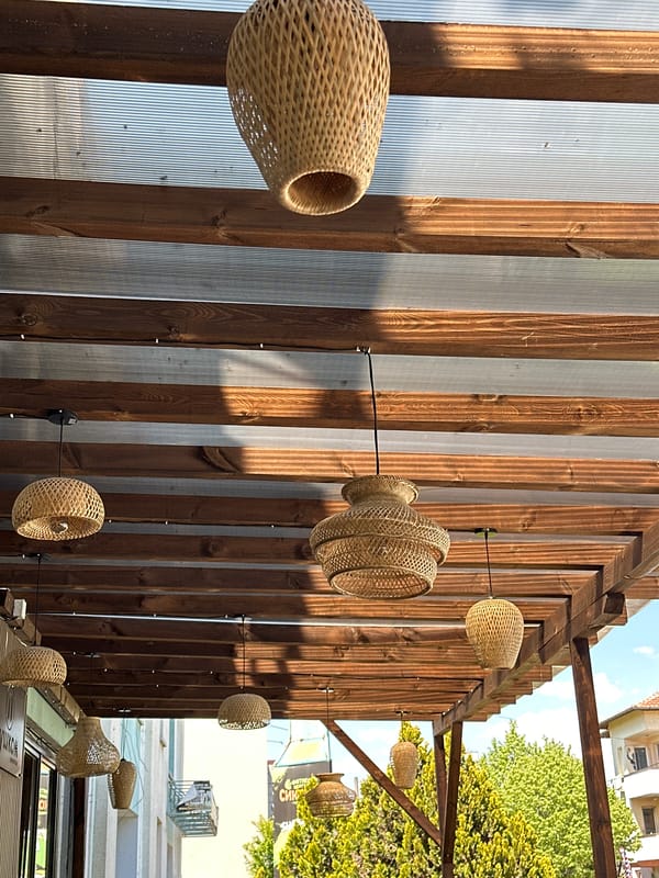 Woven wicker lamps observed hanging from wooden outdoor structure