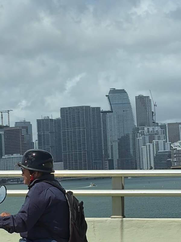 Person in motorcycle gear views Miami skyline from bridge