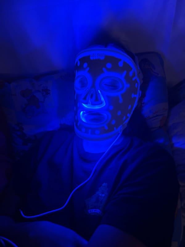 Person uses LED light therapy mask in Russian home