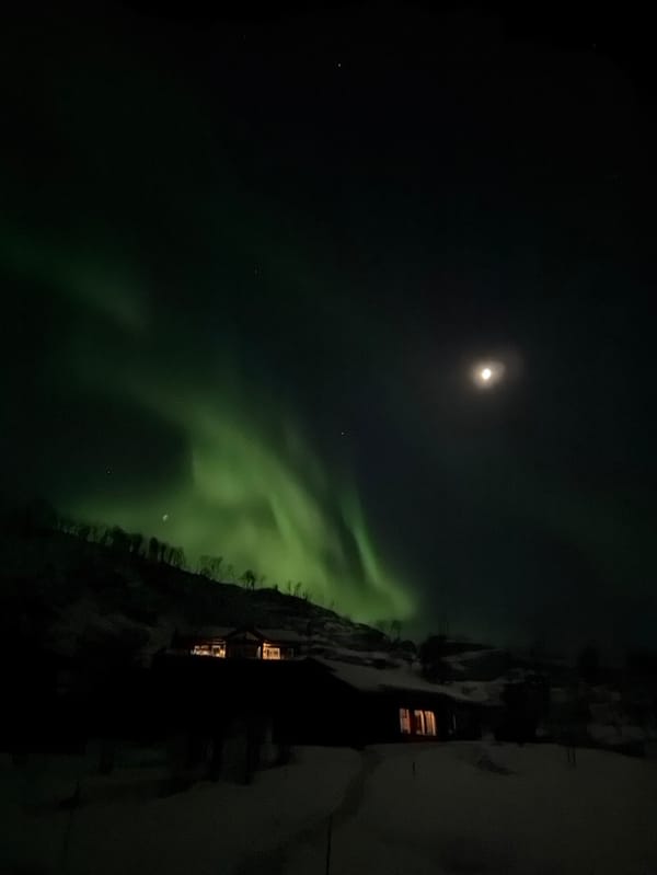 Northern lights illuminate Tromsø sky alongside bright moon