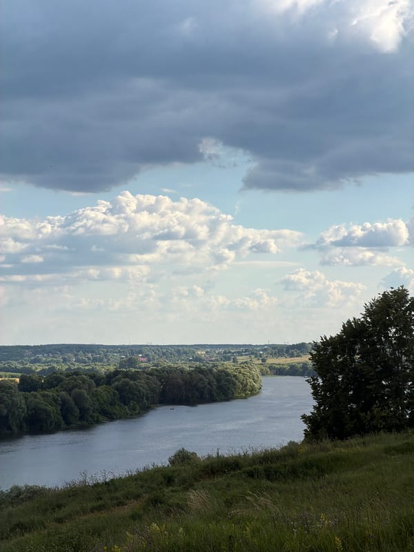 A quiet river landscape with passing boat and rolling green hills