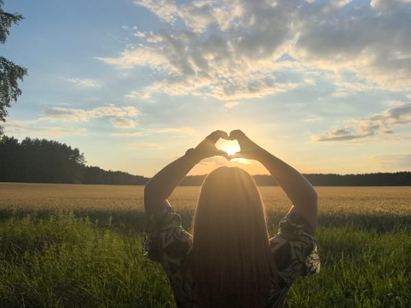 Hands frame the setting sun over a Belarusian field