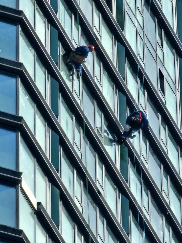 Window cleaners work Moscow high-rises as pedestrians navigate city