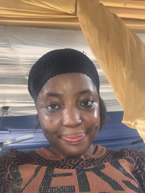 Woman photographed with fabrics and belongings in Aba