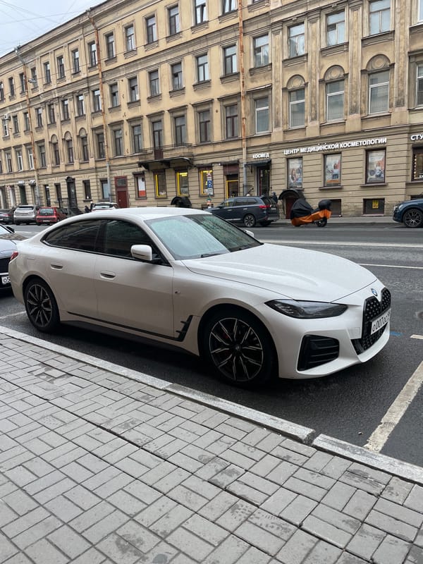 White BMW parked on cobblestone street in Saint Petersburg