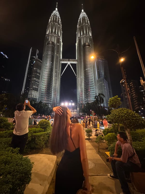 Evening crowds photograph illuminated Petronas Towers in Kuala Lumpur