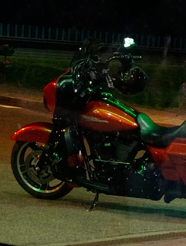 Red motorcycle parked under city lights on a quiet night