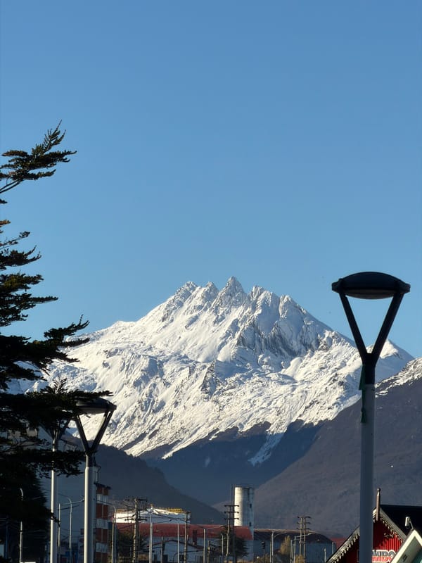Snow-covered mountain viewed through urban infrastructure in Ushuaia