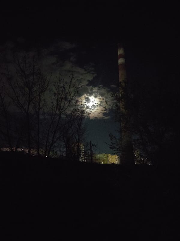 Moonlit industrial chimney observed against cloudy Yerevan sky
