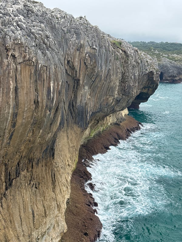 Llanes cliffs up close — rock, ocean, and crashing waves