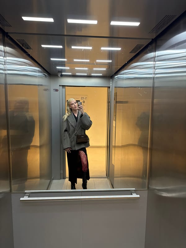 Woman takes selfie in Belgrade elevator, captured in purple-lit setting
