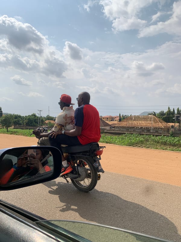 Two men ride motorcycle on Abuja road