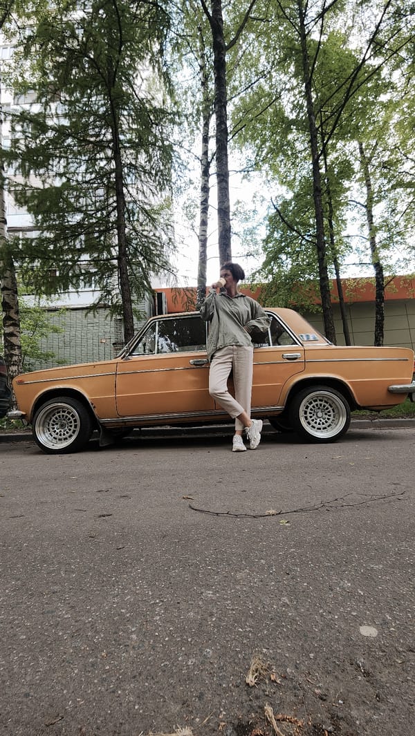 Woman takes coffee break beside vintage car in Moscow