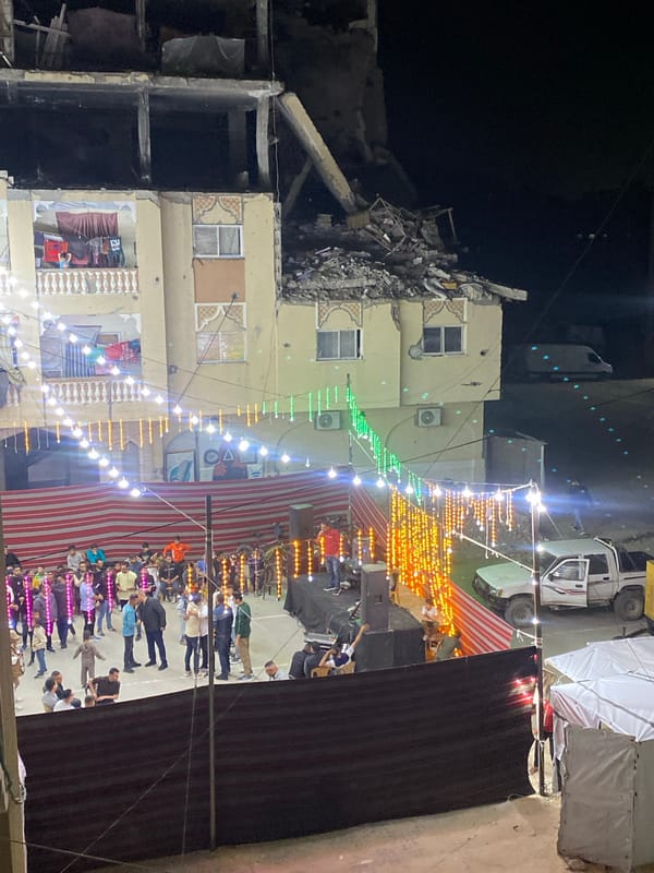 Nighttime gathering amid damaged buildings in Khan Yunis courtyard