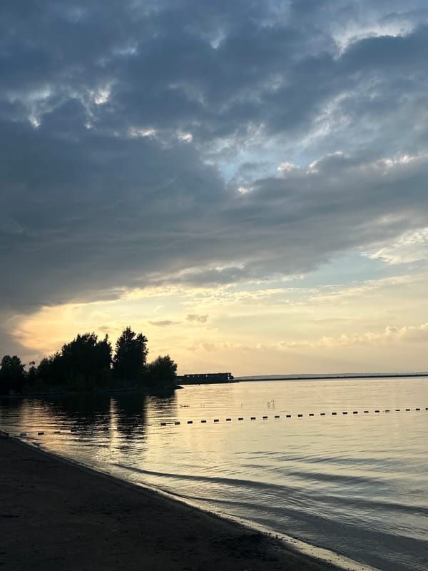 Calm waterfront at dusk, shifting skies and buoy line