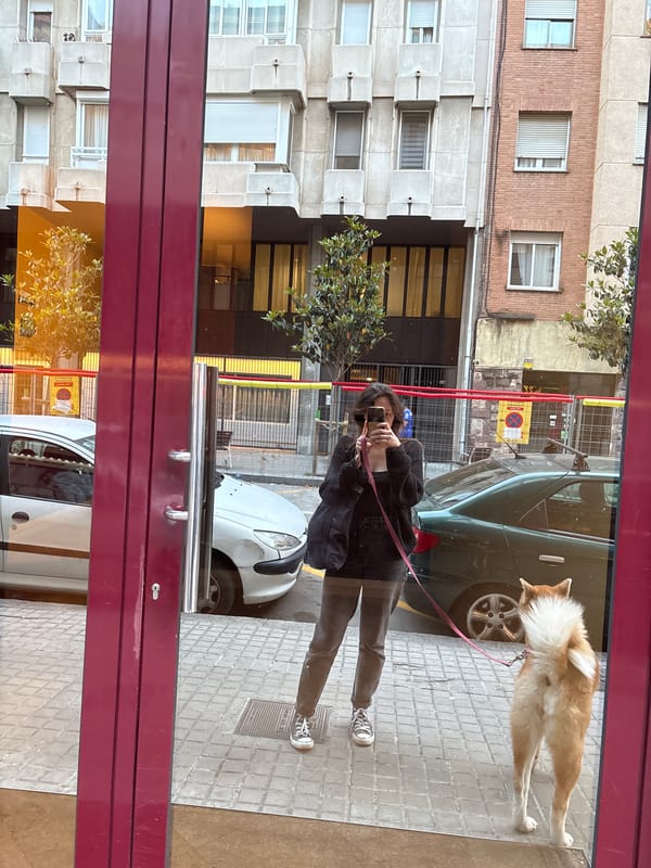 Woman takes storefront selfie while walking dog in Barcelona