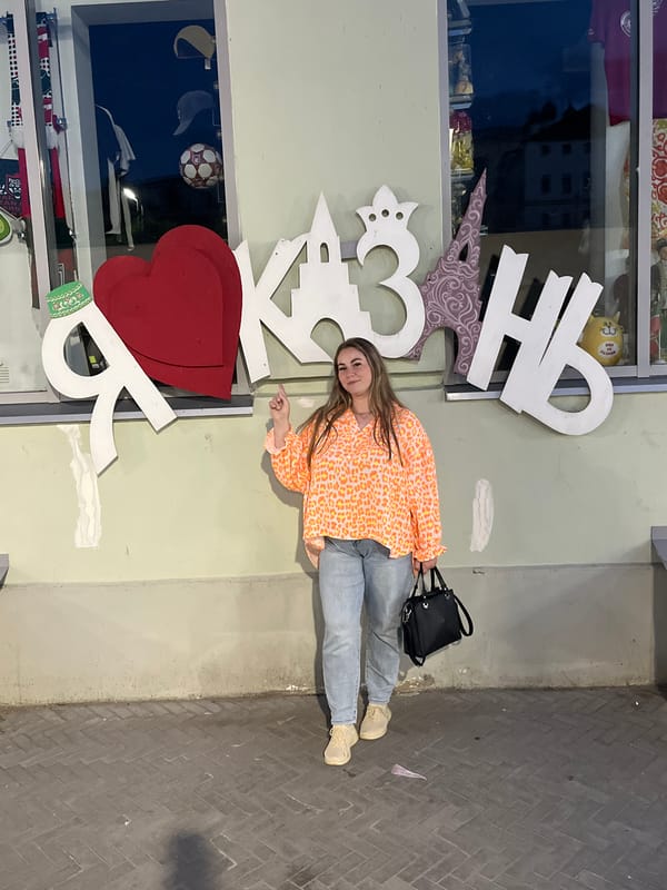 Folk art, sculptures, and storefronts along a Kazan street at dusk