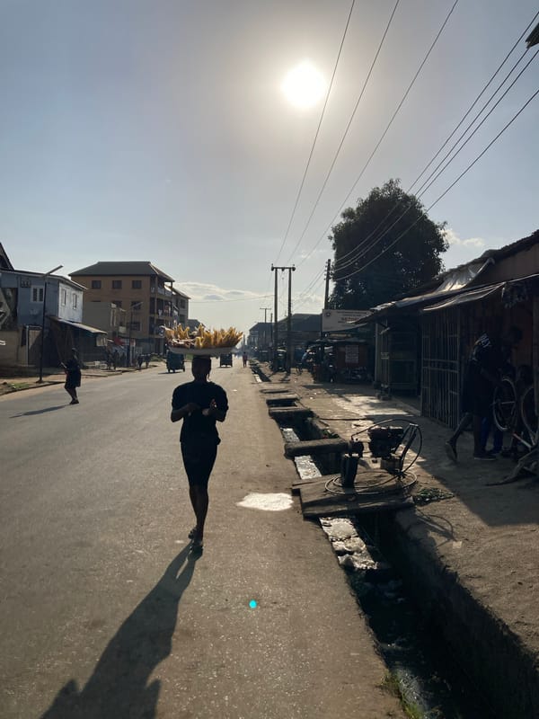Street vendor carries produce tray in sunny Aba, Nigeria