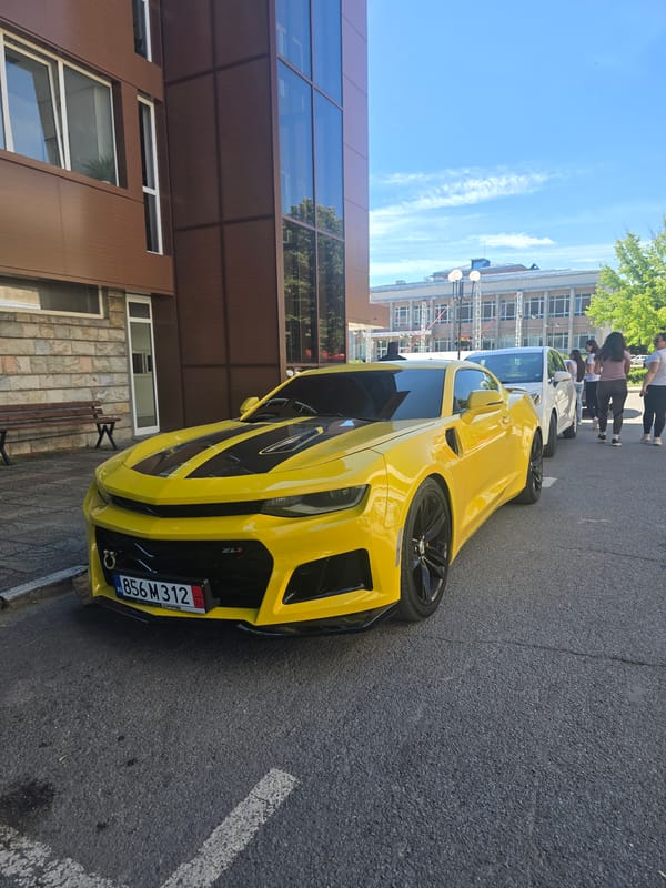 Yellow Camaro ZL1 parked outside modern building in Berkovitsa