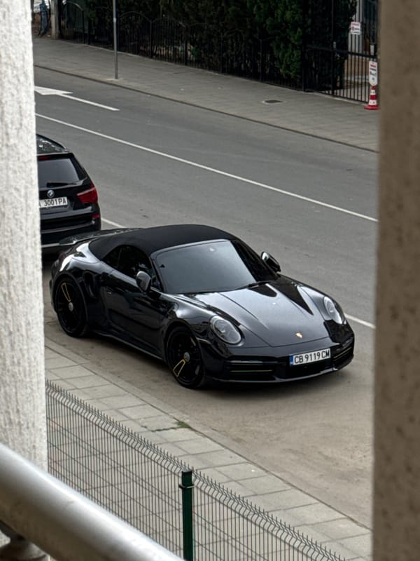 Black Porsche 911 convertible parked on rainy Nesebar streets