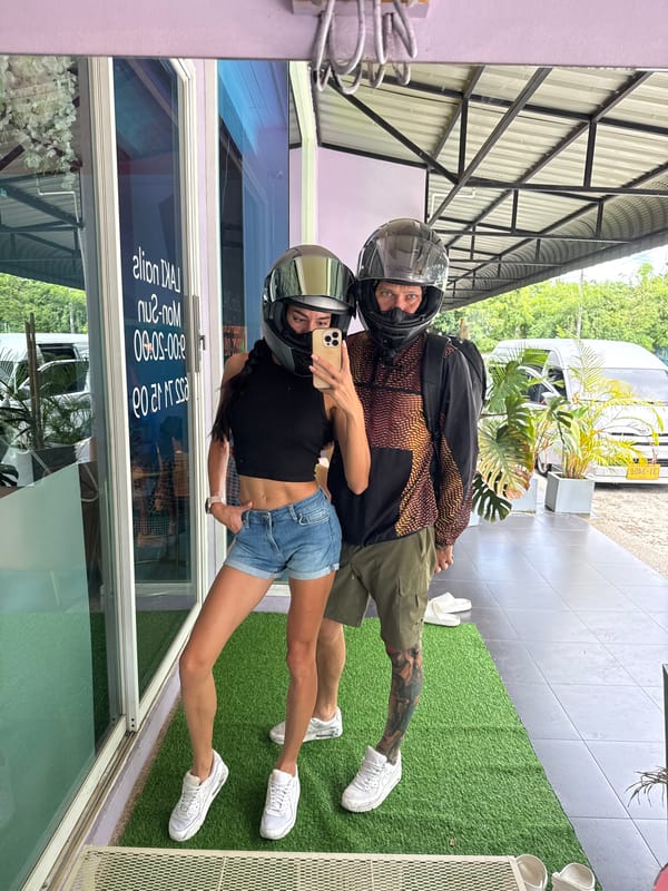 Mirror selfie with helmets on outside Wichit storefront
