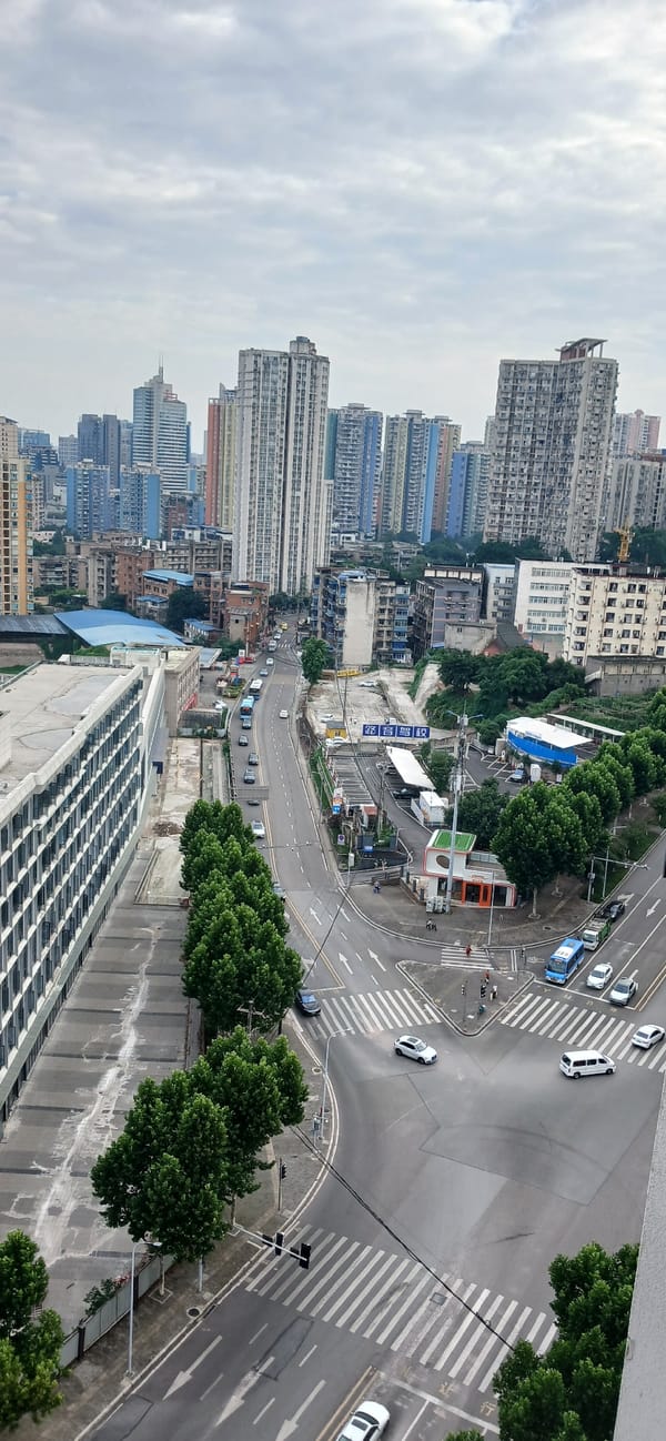 Overcast day at busy Jiulongpo intersection with airplane overhead