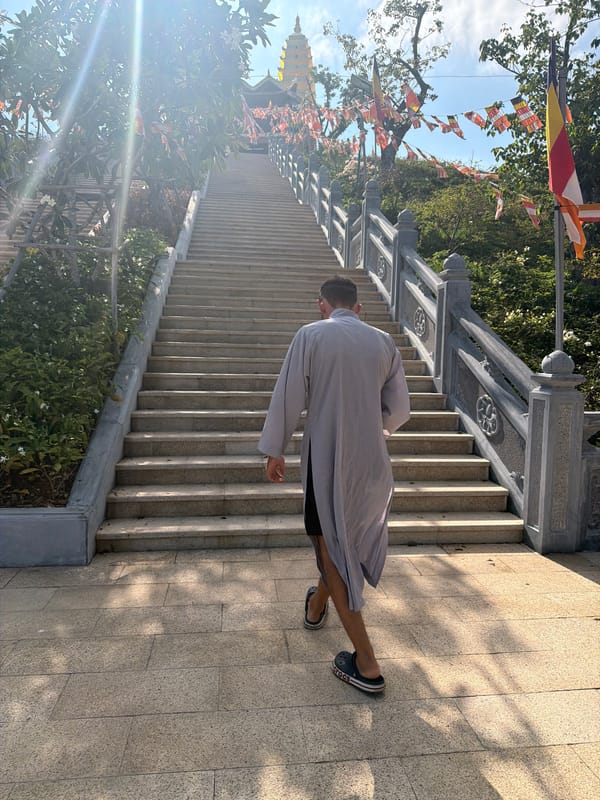 Robed man descends pagoda stairs in Nha Trang temple complex