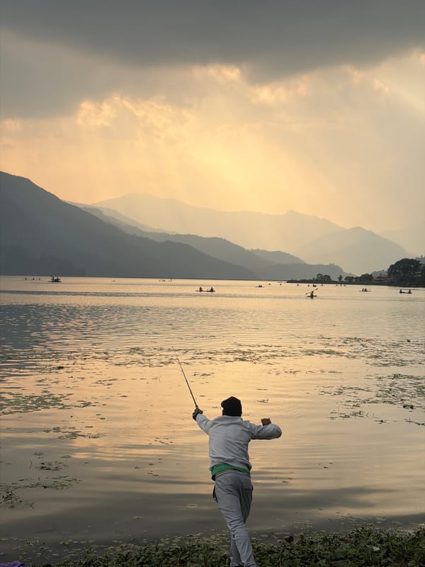 Angler fishes at Phewa Lake with Annapurna mountains backdrop