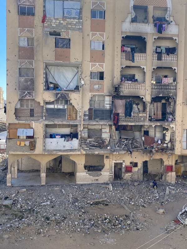 Damaged apartment building documented near debris-strewn street